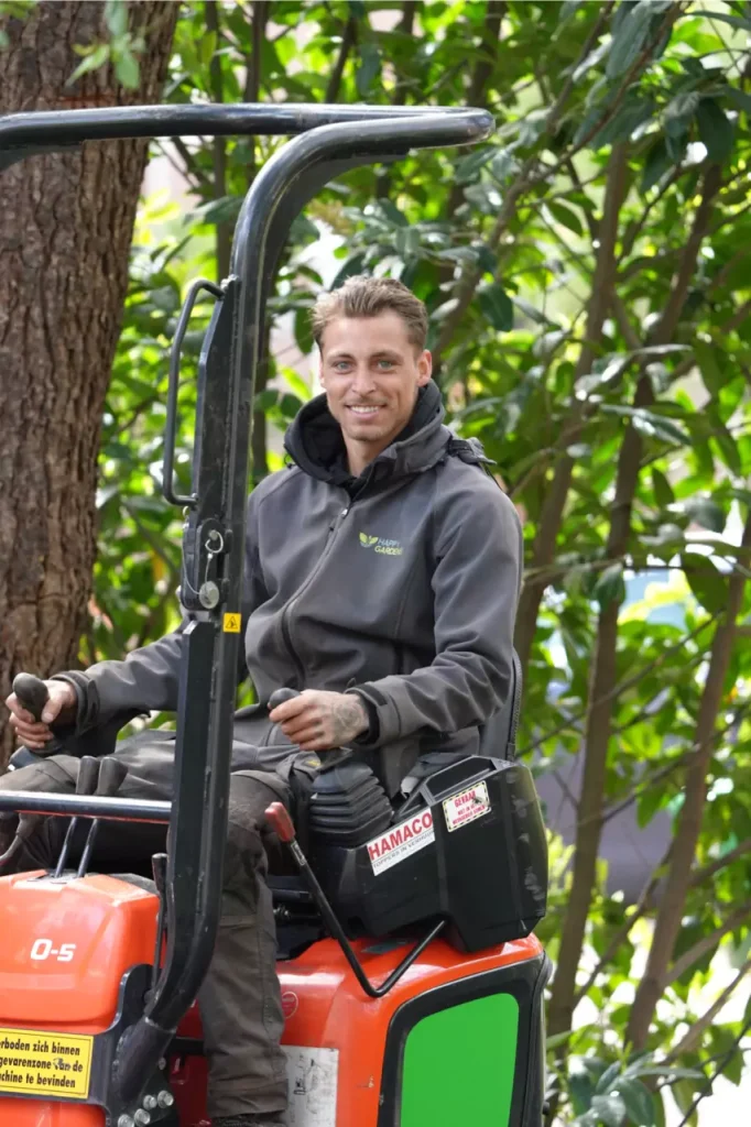 eigenaar van happy gardens bezig met grasmaaien