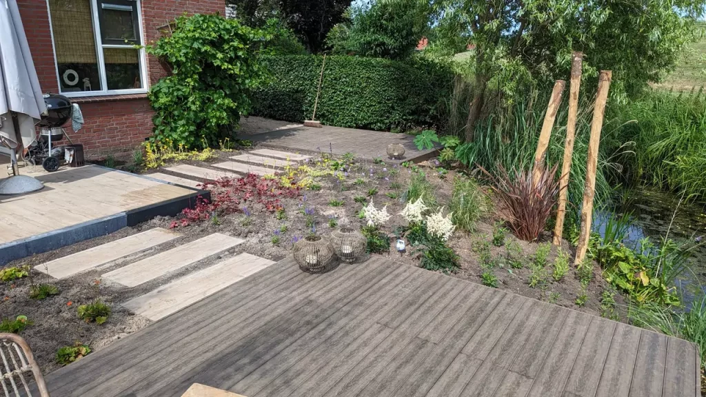 Strakke houten panelen vormen een looproute door een moderne tuin.